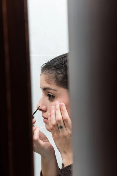 Young girl making up view through the bathroom doorway.