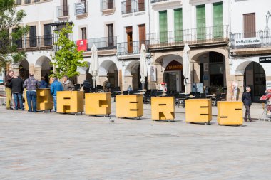 Plaza Mayor Caceres büyük sarı harfler etrafında insanlar