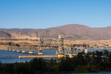 Bir kargo gemisi Columbia Nehri üzerinde Oregon Trunk Demiryolu Köprüsü altından geçer