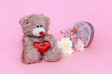 Sevgililer günü için pembe arka plan üzerinde çiçekli gri oyuncak ayı