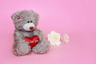 Sevgililer günü için pembe arka plan üzerinde çiçekli gri oyuncak ayı
