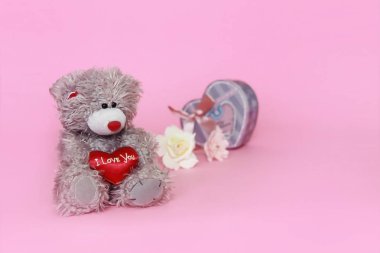Sevgililer günü için pembe arka plan üzerinde çiçekli gri oyuncak ayı