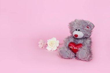 Sevgililer günü için pembe arka plan üzerinde çiçekli gri oyuncak ayı