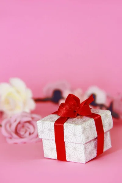 Белая Подарочная Коробка Красным Бантом Розовом Фоне Цветами — стоковое фото