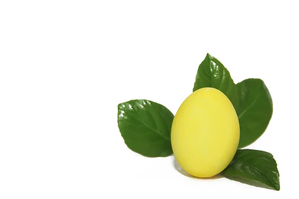 Huevo amarillo decorativo sobre hojas verdes para la fiesta de la santa Pascua — Foto de Stock