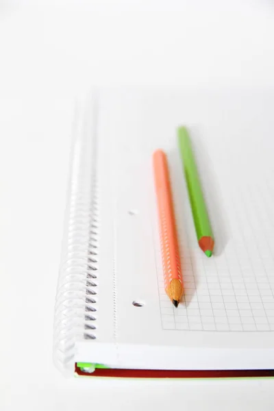 Multi-gekleurde potloden oranje groen grijs op een witte achtergrond notebook — Stockfoto