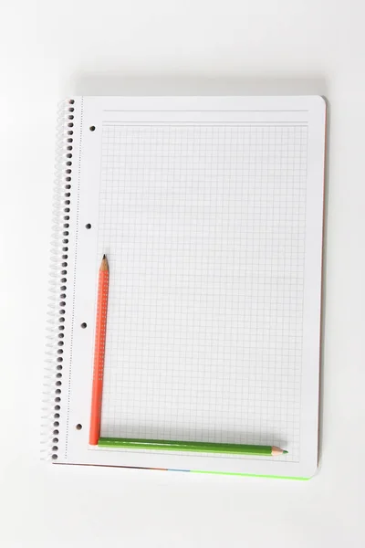 Multi-gekleurde potloden oranje groen grijs op een witte achtergrond notebook — Stockfoto