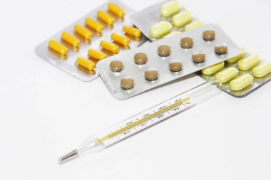 çok renkli sarı turuncu kahverengi hapları ve beyaz bir arka planda bir sıcaklık termometre