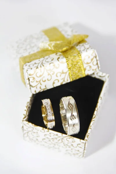 Gouden Zilveren trouwringen in een doos van de gift op een zwarte achtergrond Stockfoto