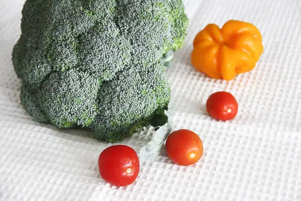 Grüner Brokkoli, rote Tomaten und orangefarbene Paprika auf weißem Hintergrund — Stockfoto