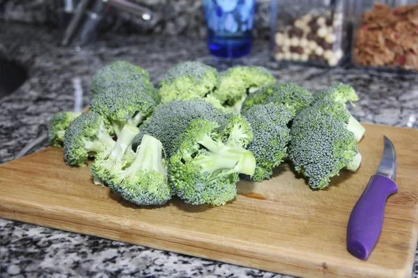 Brócolis verde e faca de cozinha em uma placa de corte de madeira — Fotografia de Stock