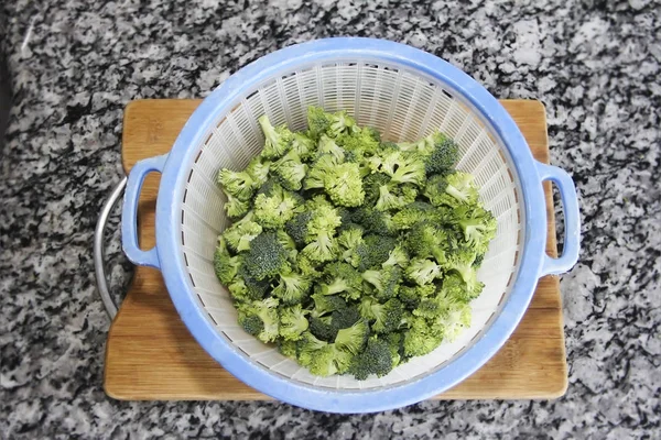 Zelená přírodní brokolice v plastové modré desce kolander — Stock fotografie