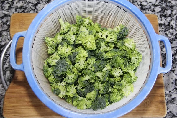 Grüner natürlicher Brokkoli in einem blauen Plastiksieb — Stockfoto