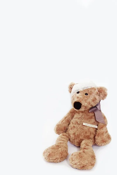 Mjuk brun leksak Björn sjuk med ett bandage på huvudet och en medicinsk termometer — Stockfoto