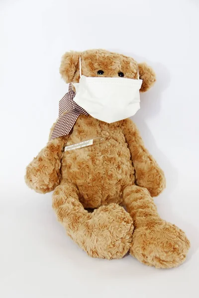 Brown soft toy bear sick with a bandage on his nose and a medical thermometer Stock Image
