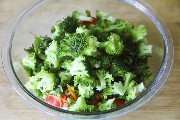 Groene broccoli salade in een glazen plaat op een houten bord achtergrond — Stockfoto