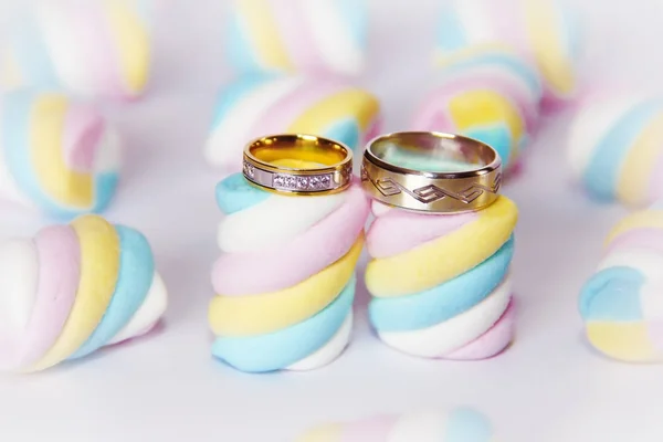 Wedding gold rings on a background of multi-colored marshmallows — Stock Photo, Image