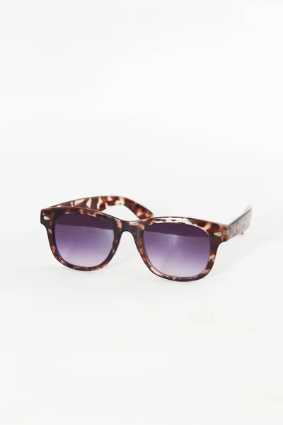 Occhiali da sole in una montatura di plastica marrone e lenti viola su uno sfondo bianco — Foto Stock