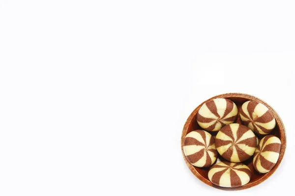 Galletas rayadas de chocolate marrón amarillo en un plato de madera marrón sobre un fondo blanco — Foto de Stock
