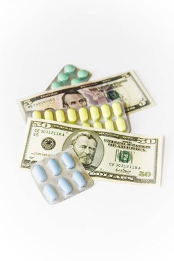 beyaz arka plan üzerinde renkli tıbbi haplar ve Amerikan doları