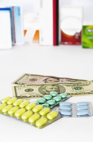 Žlutá zelená modrá medicína pilulky a americké dolary na bílém pozadí — Stock fotografie