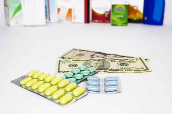 Amarillo verde azul píldoras médicas y dólares americanos sobre fondo blanco —  Fotos de Stock