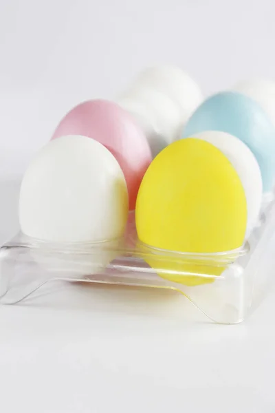 Multi-colored white yellow pink blue chicken eggs in a container — Stock Photo, Image