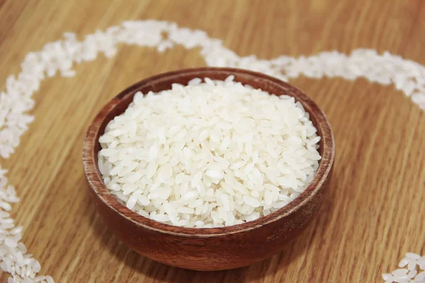 Biały ryż w drewnianej płycie i wzór ryżu w kształcie serca — Zdjęcie stockowe
