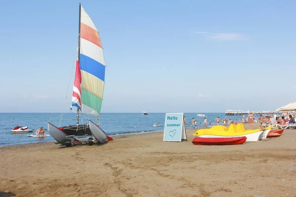 Парусный катамаран с разноцветным флагом на фоне синего моря — стоковое фото