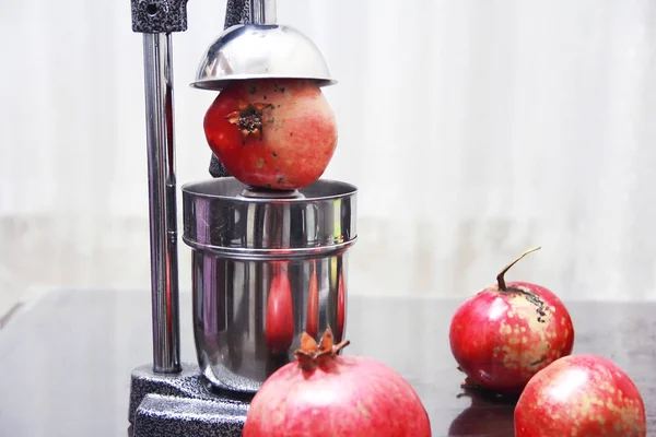 Rote Granatapfelfrüchte und Metallsaftpresse im Wohnbereich — Stockfoto