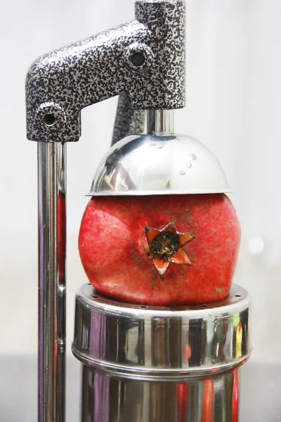 Frutas de granada roja y exprimidor de mano de metal en el interior del hogar —  Fotos de Stock