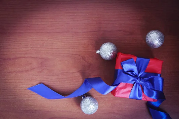 Rode geschenk doos met blauwe strik op de achtergrond van Kerstmis speelgoed voor het nieuwe jaar vakantie — Stockfoto