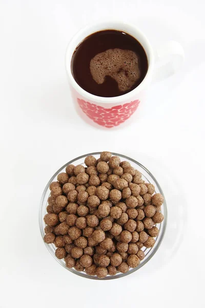 Bolas de maíz de chocolate en un plato de vidrio y taza de cacao para el desayuno — Foto de Stock