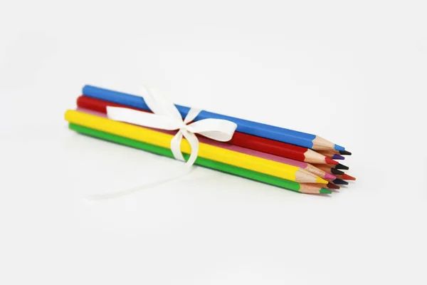 Crayons en bois multicolores pour dessiner avec arc blanc sur fond blanc — Photo