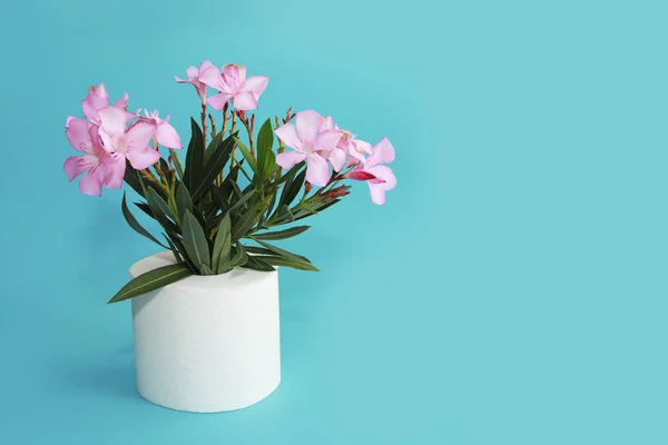 Rollo de papel higiénico y flores rosadas sobre un fondo azul — Foto de Stock