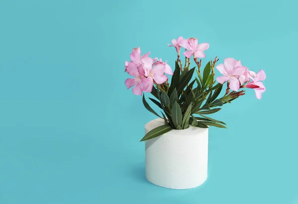 Rollo de papel higiénico y flores rosadas sobre un fondo azul — Foto de Stock