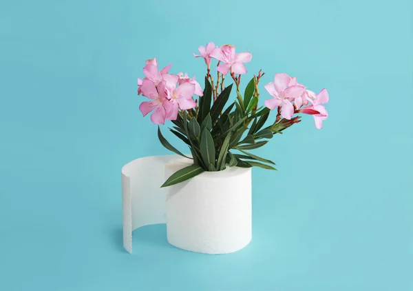 Rollo de papel higiénico y flores rosadas sobre un fondo azul — Foto de Stock