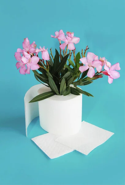 Rollo de papel higiénico y flores rosadas sobre un fondo azul — Foto de Stock