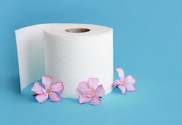 Rollo de papel higiénico blanco con decoración de flores sobre un fondo azul — Foto de Stock