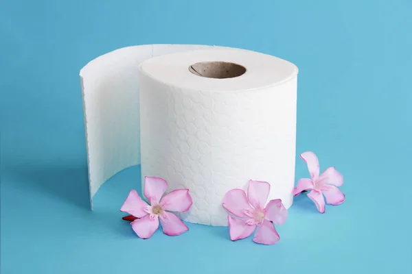 Rollo de papel higiénico blanco con decoración de flores sobre un fondo azul — Foto de Stock