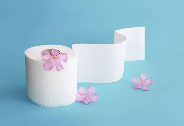 Bílý toaletní papír s květinami dekoracemi na modrém pozadí — Stock fotografie