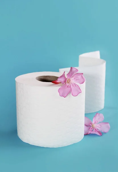 Rollo de papel higiénico blanco con decoración de flores sobre un fondo azul — Foto de Stock