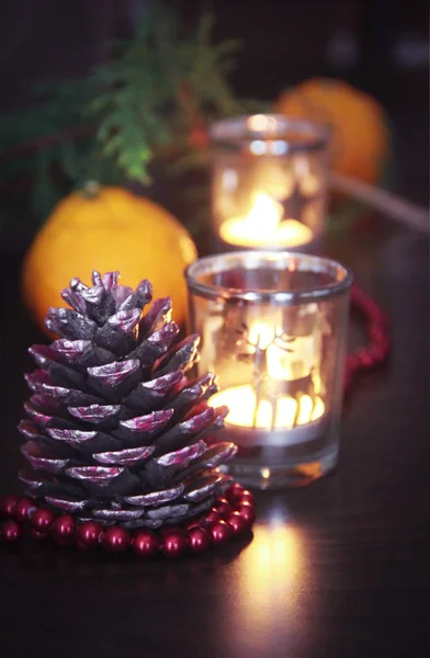Christmas candles in a glass candlestick with a decor of pine cones and tangerines — Stock Photo, Image