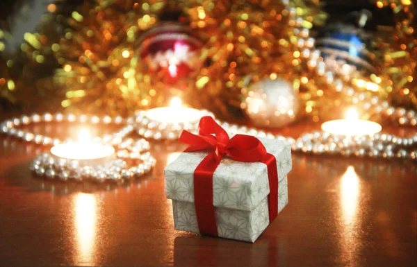 Різдвяна подарункова коробка з червоним бантом і свічками з новорічним декором — стокове фото