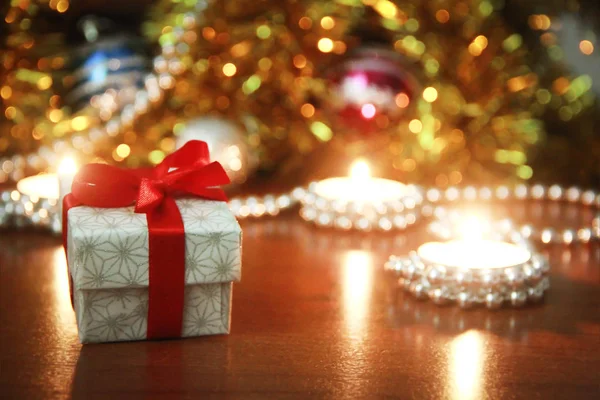 Різдвяна подарункова коробка з червоним бантом і свічками з новорічним декором — стокове фото
