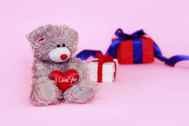 elinde kırmızı bir kalp ve hediyeler ile bir kutu ile oyuncak oyuncak kabarık ayı