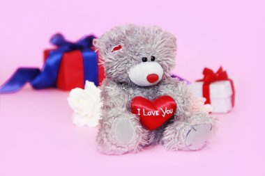 elinde kırmızı bir kalp ve hediyeler ile bir kutu ile oyuncak oyuncak kabarık ayı