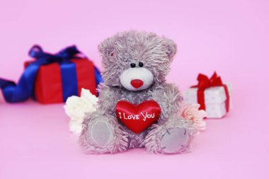 elinde kırmızı bir kalp ve hediyeler ile bir kutu ile oyuncak oyuncak kabarık ayı