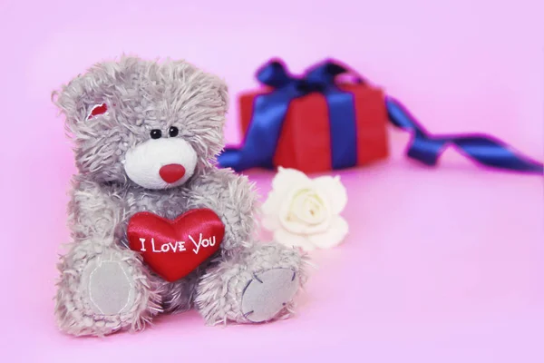 Jouet ours pelucheux en peluche avec un coeur rouge dans les mains et une boîte avec des cadeaux — Photo