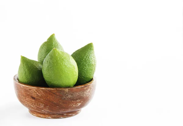 Фрукти зеленого натурального лимона лайма в дерев'яній коричневій тарілці — стокове фото